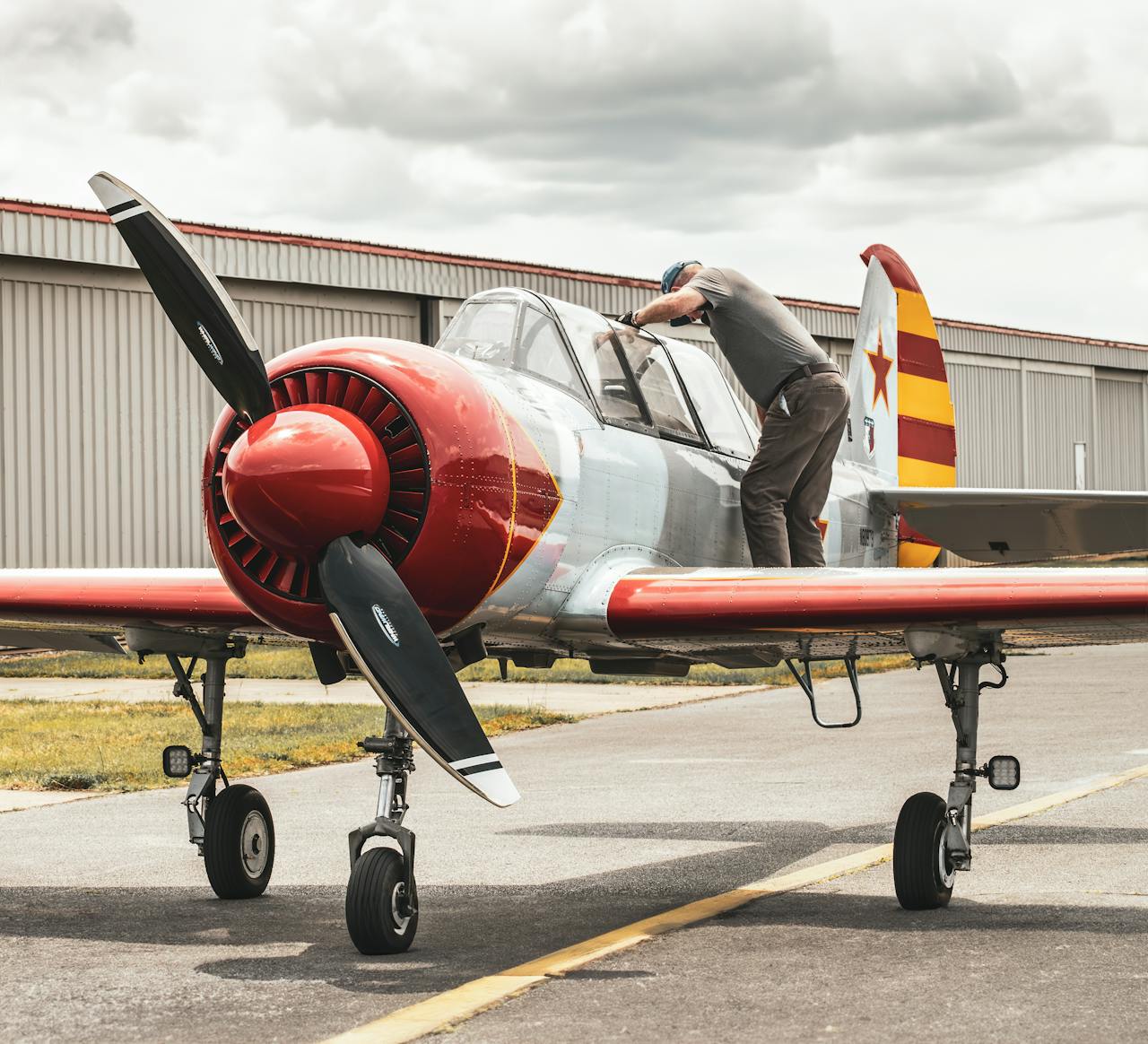 A pilot examining a Yakovlev Yak-52 aircraft on the tarmac in Raleigh, NC.